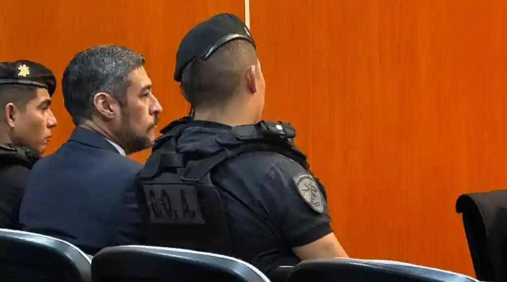 Claudio Parisi custodiado por dos policías en un juicio que no es ni penal ni judicial